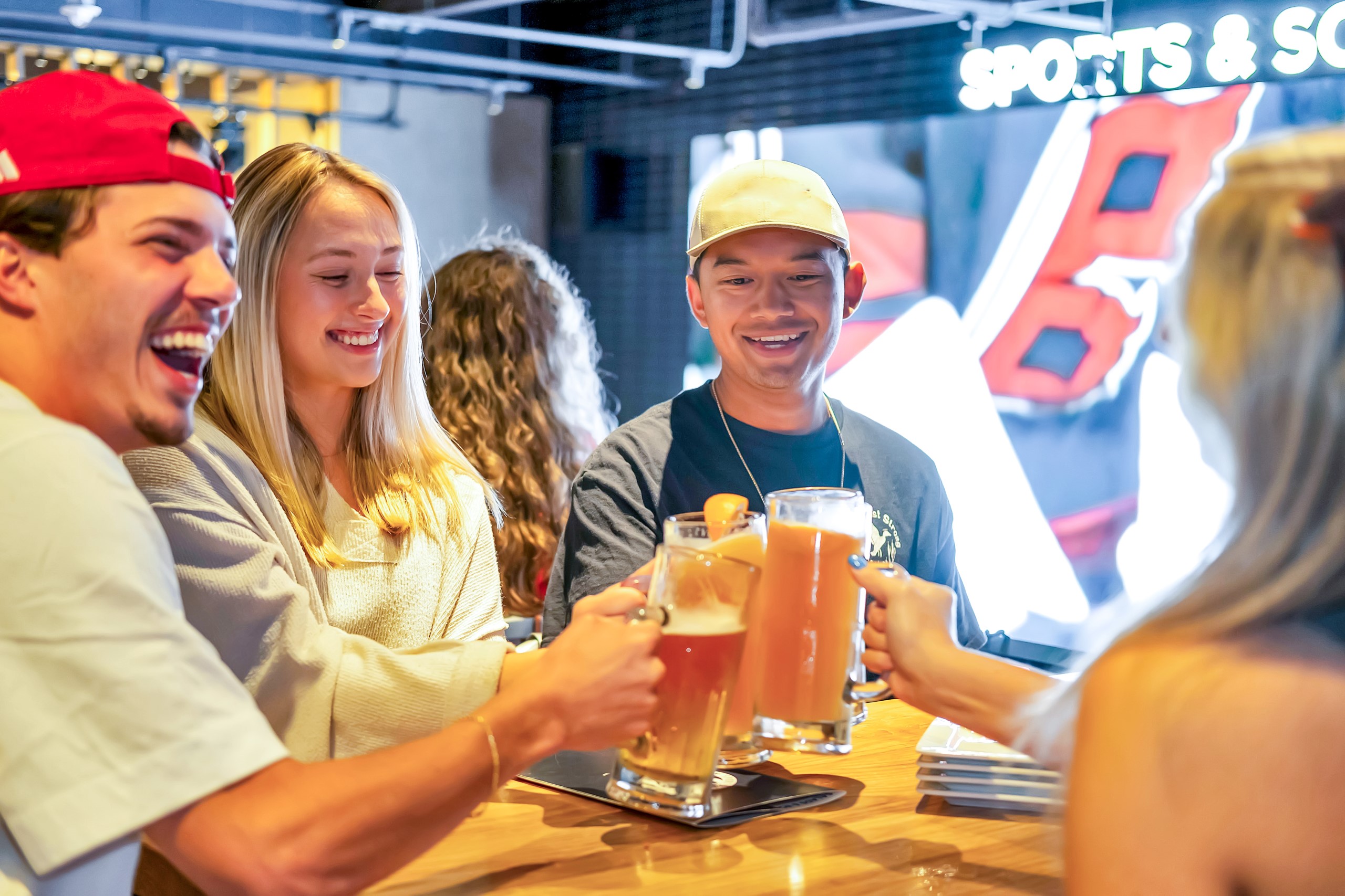 Group of guests holding beers at Sports & Social Cary