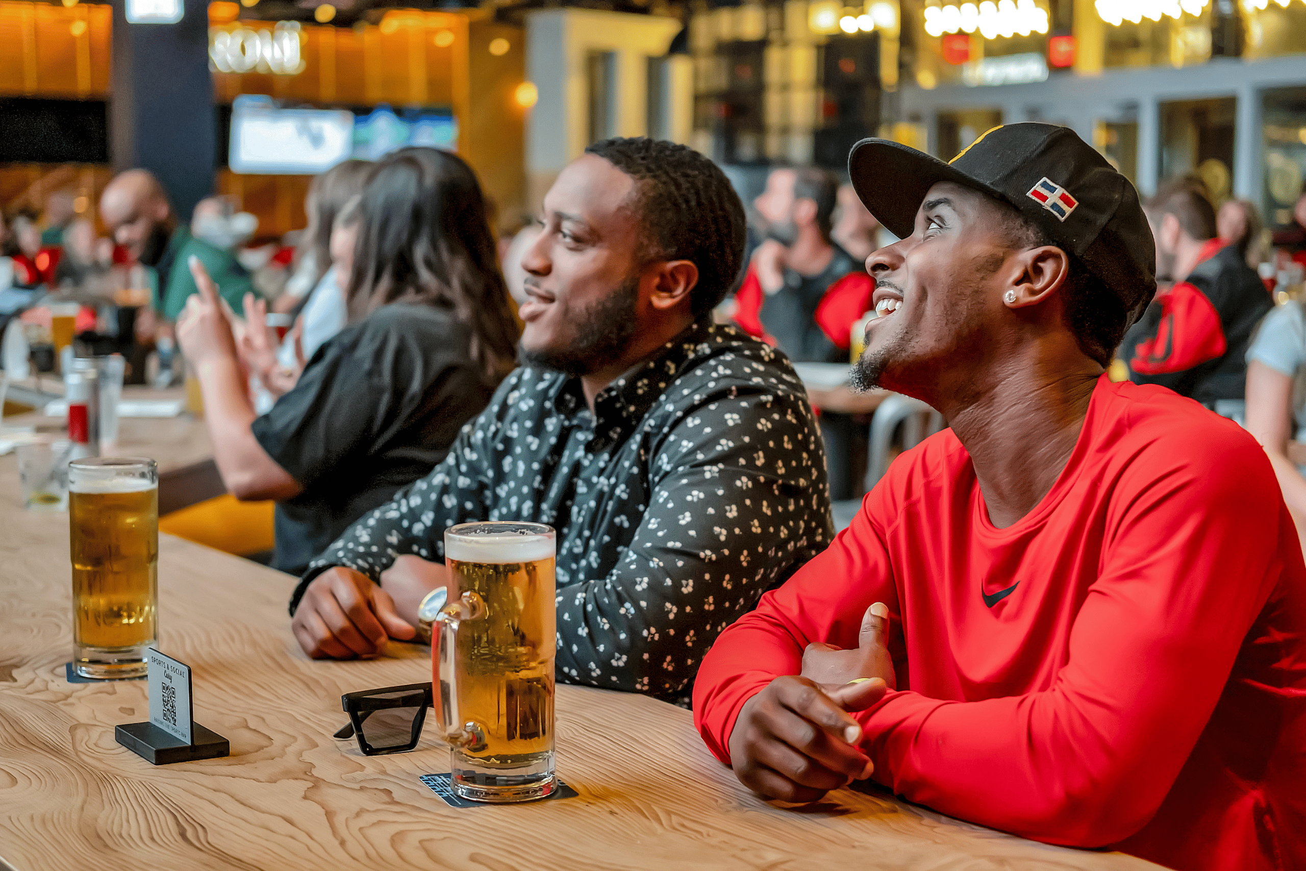 Two men sitting at the bar with mugs of beer at Sports & Social in Cary, NC.