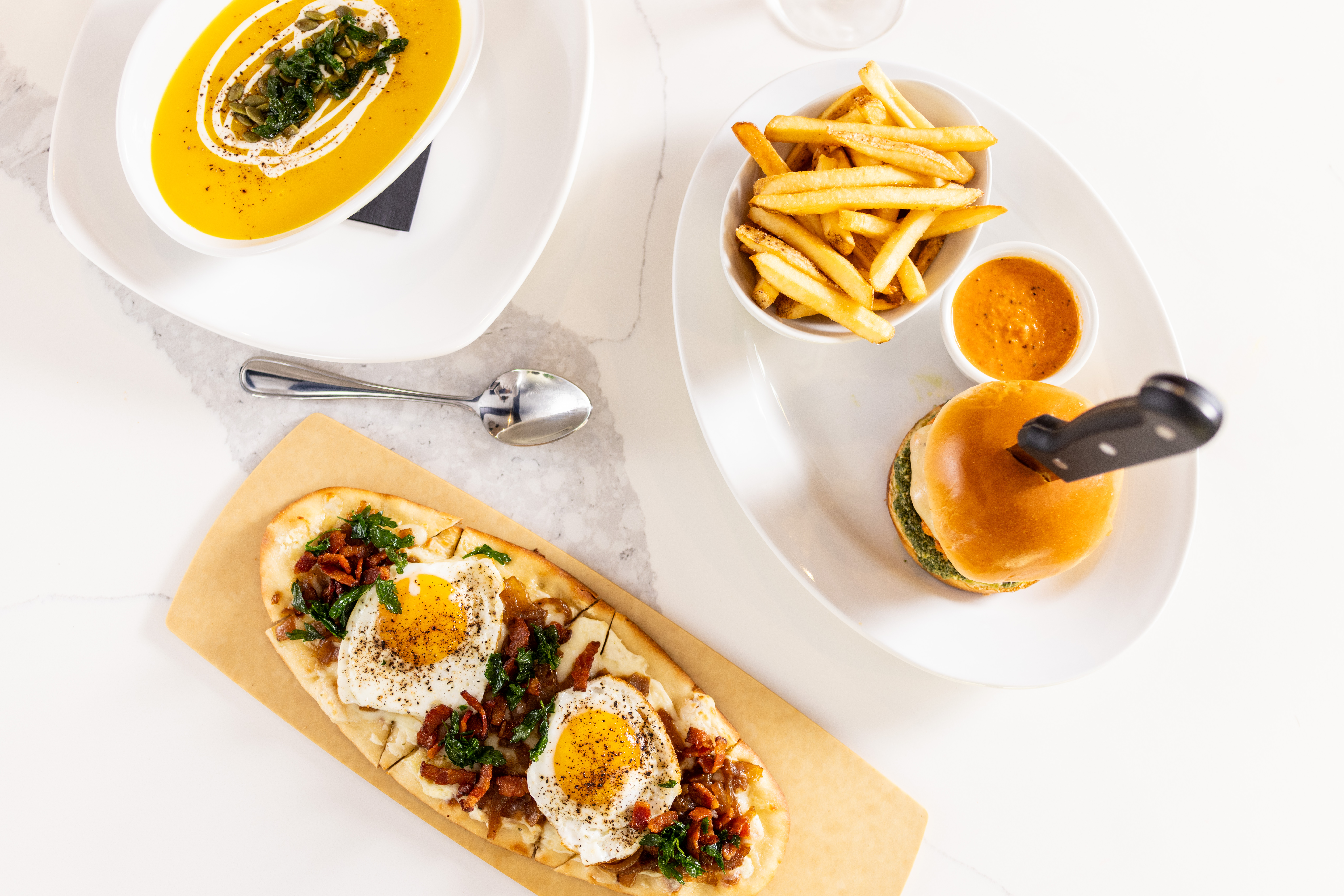 Roasted Butternut Soup, Carbonara Flatbread, Wagyu Meatball Burger, and Fries on White Dishes